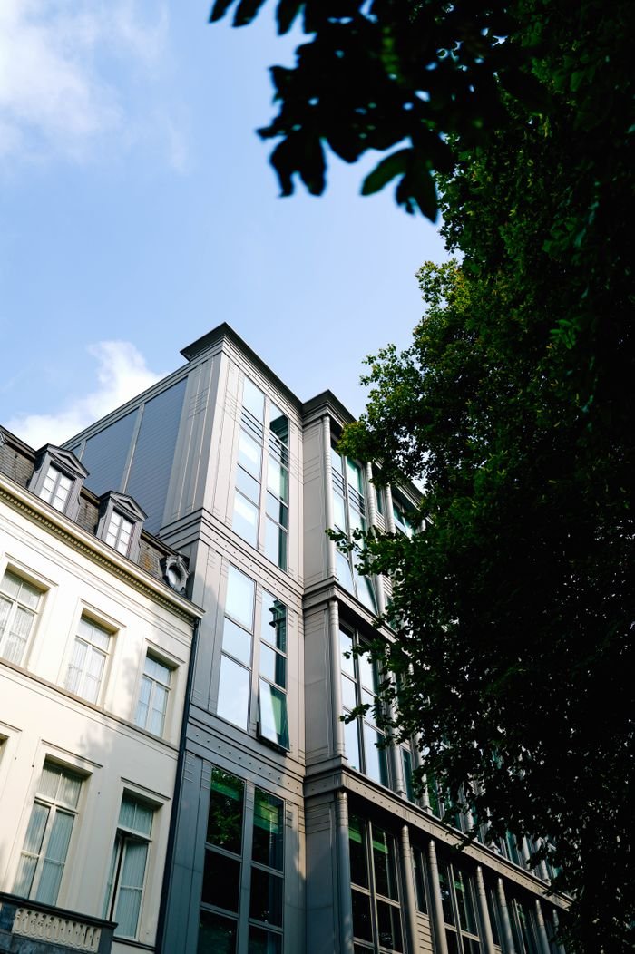 Modern city architecture with glass windows, trees, and blue sky.