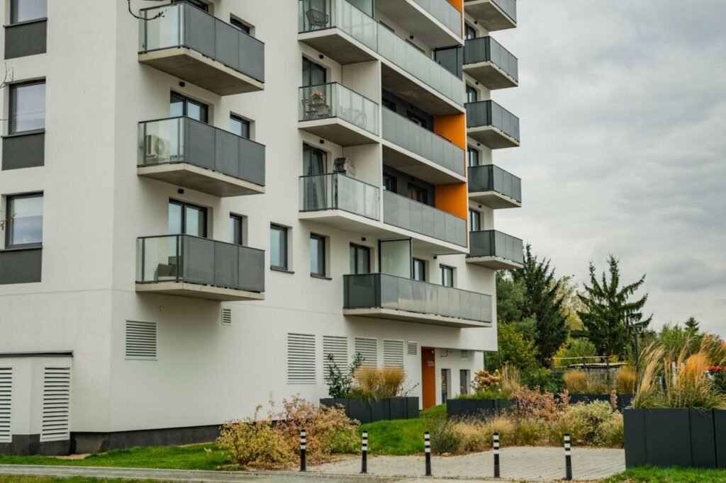 Contemporary apartment complex featuring glass balconies and landscaped surroundings.