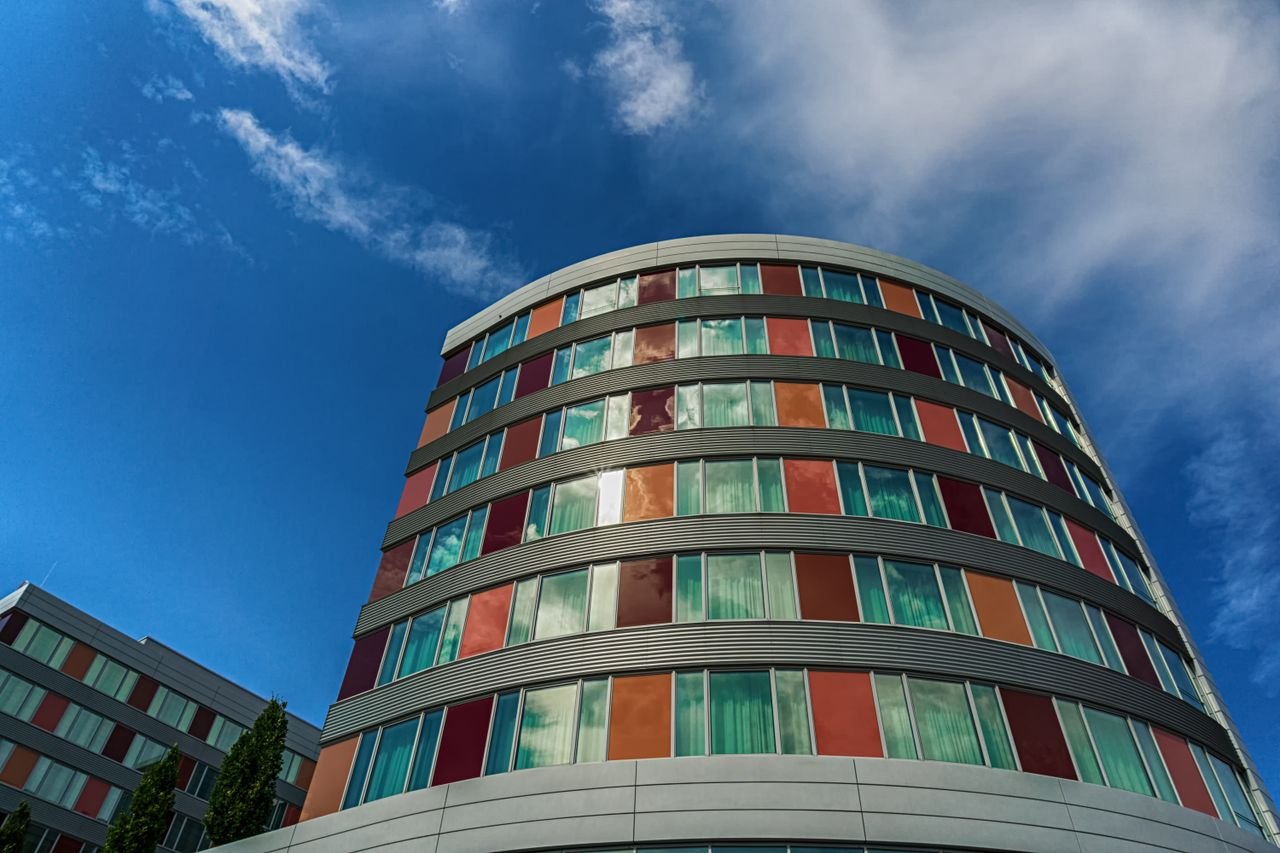 mobile-01 A modern curved building with colorful panels against a blue sky, showcasing urban architecture.